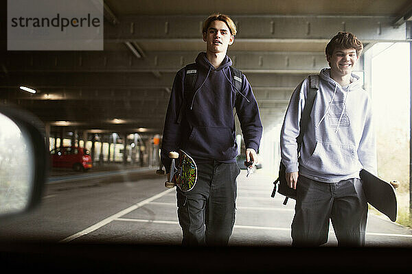 Teenager mit Skateboards auf einem Parkplatz