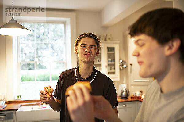 Glückliche Teenager-Jungs essen Pizza in der Küche