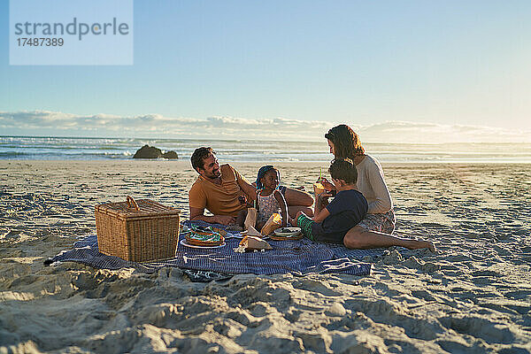 Familie genießt Picknick-Mittagessen am sonnigen Meeresstrand