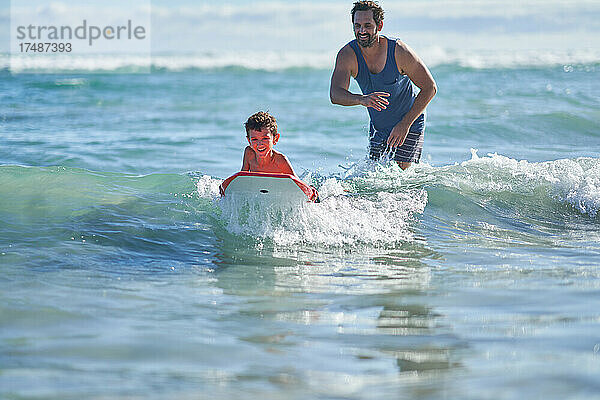 Glücklicher Vater und Sohn beim Bodyboarden im sonnigen Meer