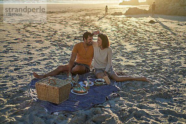 Verliebtes Paar beim Picknick am sonnigen Strand