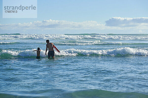 Vater und Sohn beim Bodyboarding im sonnigen Sommermeer