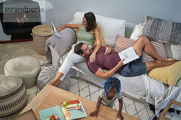 Familie entspannt und liest auf dem Wohnzimmersofa