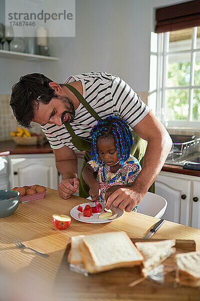 Vater hilft Tochter beim Obstschneiden in der Küche
