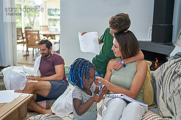 Familie liest und malt im Wohnzimmer