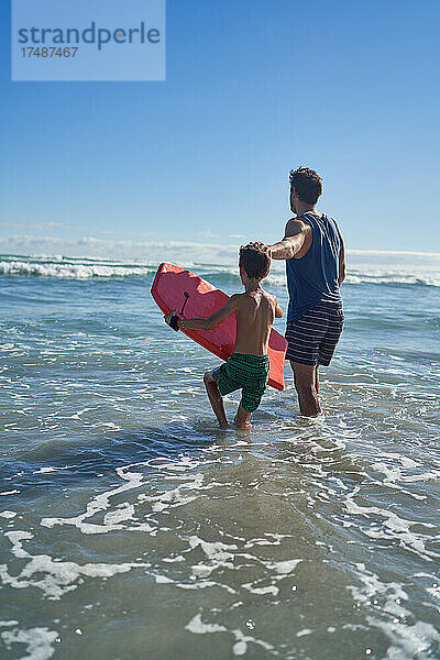 Vater und Sohn mit Bodyboard im sonnigen Sommermeer