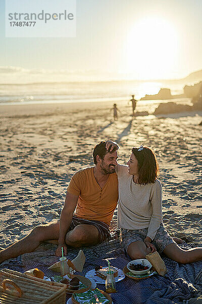 Glückliches  zärtliches Paar beim Picknick am sonnigen Strand