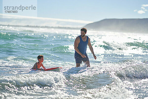 Vater und Sohn beim Bodyboarding in der sonnigen Sommerbrandung