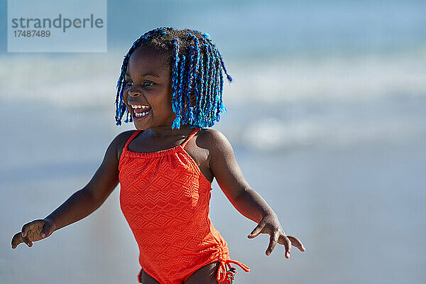Glückliches süßes Kleinkind Mädchen mit blauen Zöpfen im Badeanzug