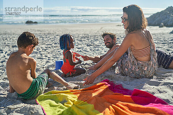 Familie spielt im Sand am sonnigen Sommerstrand