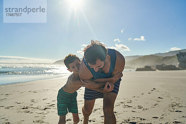 Glücklicher Vater und Sohn umarmen sich am sonnigen Sommerstrand