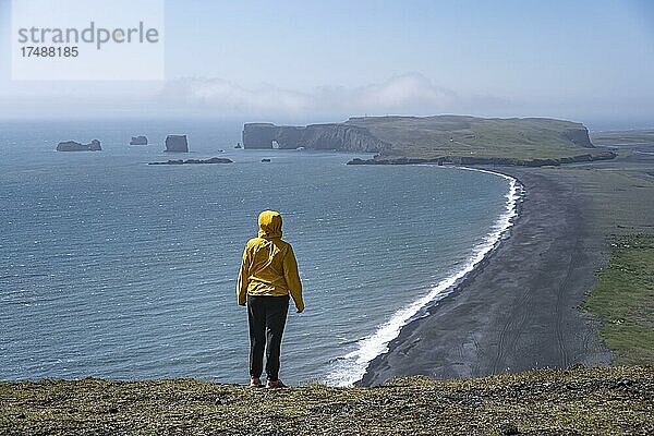 Junge Frau blickt über den Reynisfjara Strand  Schwarzer Sandstrand  Dyrhólaey  Südisland  Island  Europa