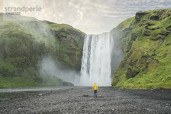 Riesiger Wasserfall hinter einem Menschen  Wasserfall Skógafoss  Südisland  Island  Europa