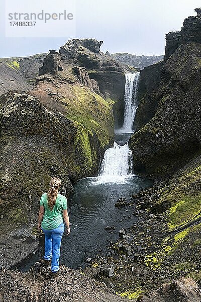 Wanderin vor Wasserfall in einer Schlucht  Landschaft am Fimmvörðuháls Wanderweg  Südisland  Island  Europa