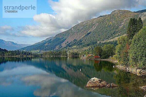 Häuser und Berge spiegeln sich in einem ruhigen See  Gaulartal. Norwegen
