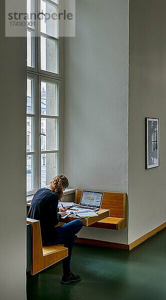 Eine Studentin sitzt zum Lernen mit ihrem Laptop am Fenster in dem Gebäude der Humboldt Universität  Berlin  Deutschland  Europa