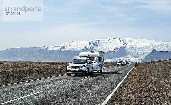 Auto mit Wohnwagenanhänger auf Landstraße  hinten riesiger Vatnajökull Gletscher  Ringstraße  Island  Europa