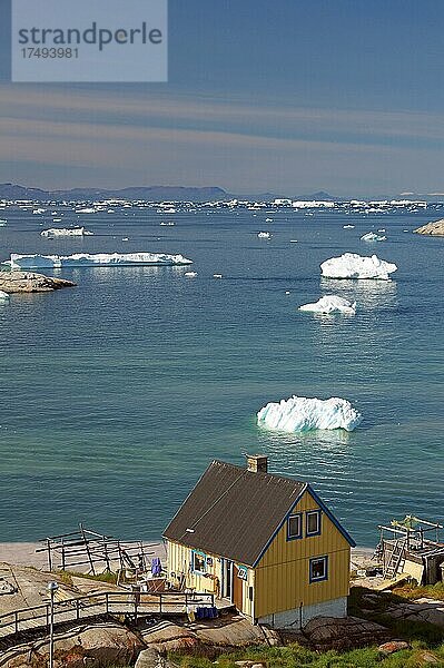 Einfaches Wohnhaus am Rande einer mit Eisbergen bedeckten Bucht  Ilulissat  Arktis  Diskobucht  Grönland  Dänemark  Nordamerika