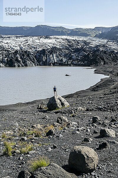 Wanderer steht auf Felsen vor Gletscherzunge Sólheimajökull am Gletscher Mýrdalsjökull  Suðurland  Island  Europa