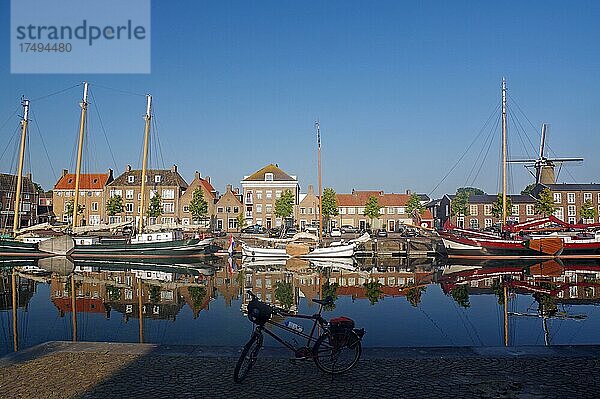 Fahrrad vor alten Schiffen  Häusern und einer Mühle  die sich spiegeln im Hafenbecken  Morgenstimmung  Hellevoetsluis  Südholland  Niederlande  Europa