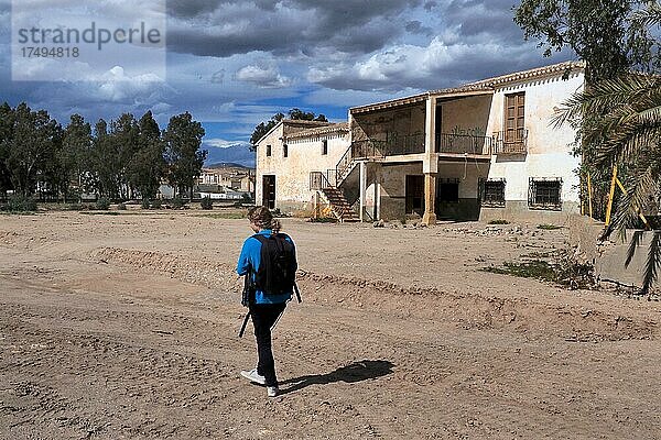 Frau auf dem Grundstück vor einem verlassenen Haus  Lost Place