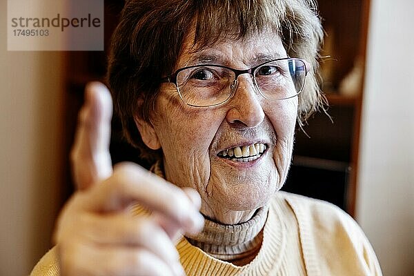 Seniorin mit erhobenen Zeigefinger zuhause in ihrem Wohnzimmer  Köln  Nordrhein-Westfalen  Deutschland  Europa