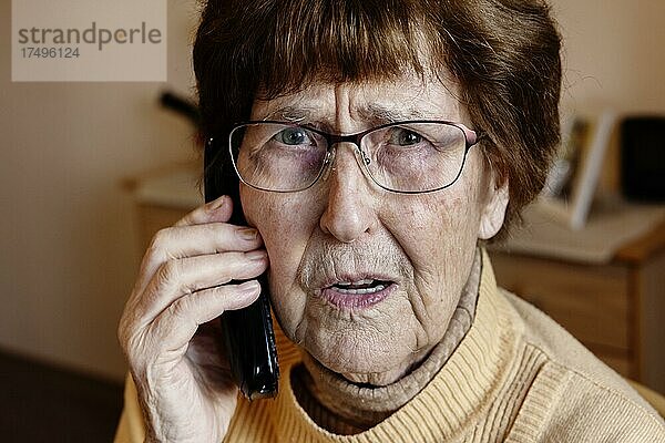 Seniorin zuhause beim Telefonieren schaut sorgenvoll  Enkeltrick  Köln  Nordrhein-Westfalen  Deutschland  Europa