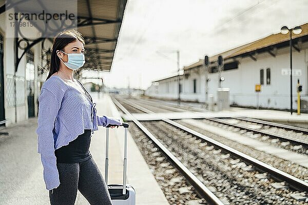 Junge Frau mit Maske und Gepäck wartet am Bahnhof  Portugal  Europa