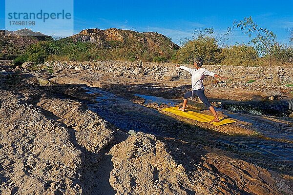 Frau macht Yoga auf Matte am Fluss  Yoga im Freien  Yogaübung in der Natur  Andalusien  Spanien  Europa