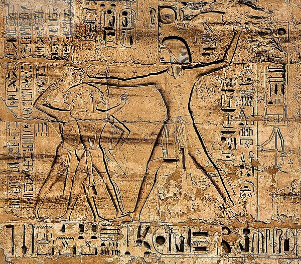 Gefangene  an den Haaren baumelnd  beim Erschlagen werden  1. Pylon mit übergroßen Darstellungen  die den Pharao in den typischen Machtdarstellungen beim Erschlagen der Feinde zeigen  Medinet Habu  Totentempel Ramses III. Luxor  Theben-West  Ägypten  Luxor  Theben  West  Ägypten  Afrika