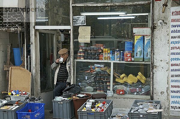 Alter Mann trinkt Tee vor seinem Laden mit Gebrauchswaren  Teetrinker vor Ladentür  Stadtteil Eminönü  Istanbul  Türkei  Asien