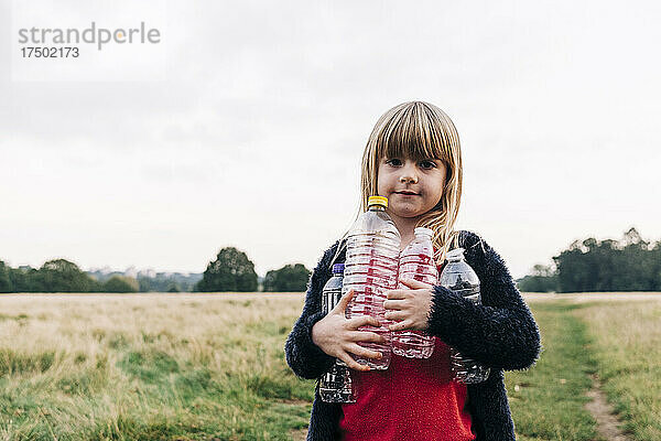 Mädchen mit Plastikflaschen steht im Park