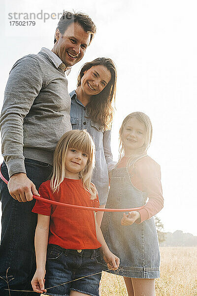 Glückliche Eltern und Töchter mit Hula Hoop im Park an einem sonnigen Tag