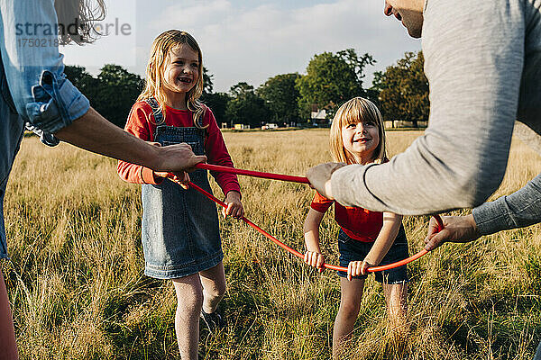 Töchter und Eltern halten Hula-Hoop beim Spielen im Park
