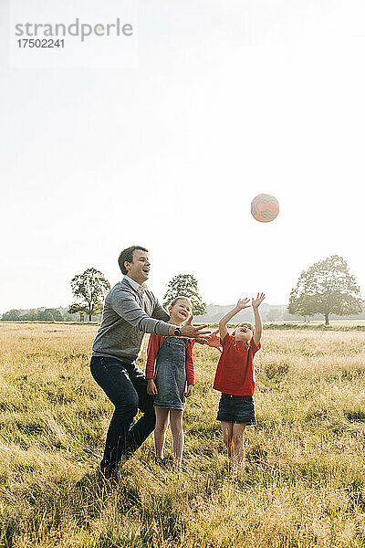 Vater und Töchter spielen mit Ball im Park