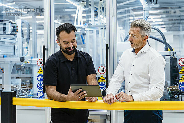 Geschäftsleute nutzen Tablet-PC am Geländer in der Fabrik