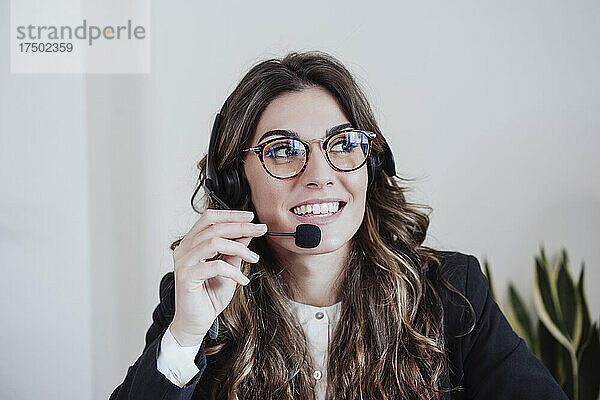 Kundendienstmitarbeiter mit Brille spricht im Büro über Headset