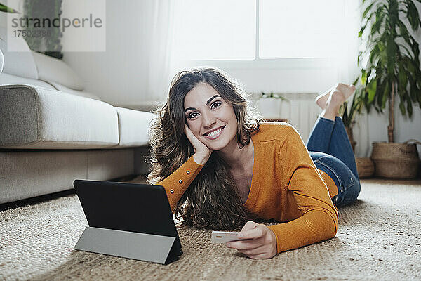 Frau hält zu Hause Kreditkarte per Tablet-PC in der Hand
