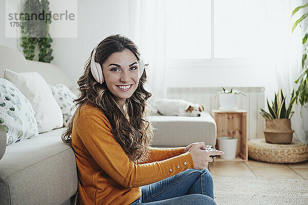 Lächelnde Frau mit Kopfhörern  die ein Spiel mit Joystick spielt