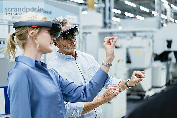Kollegen diskutieren und verwenden Augmented-Reality-Brillen in der Fabrik