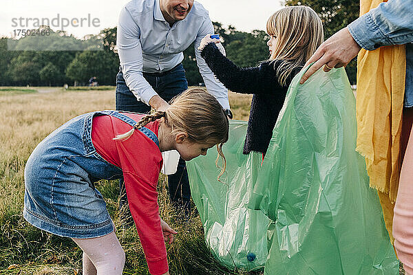 Töchter helfen Eltern beim Müllsammeln im Park