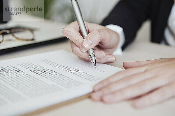 Immobilienmakler unterzeichnet Dokument im Büro