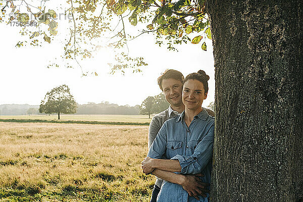 Paar steht an einem sonnigen Tag am Baum im Park