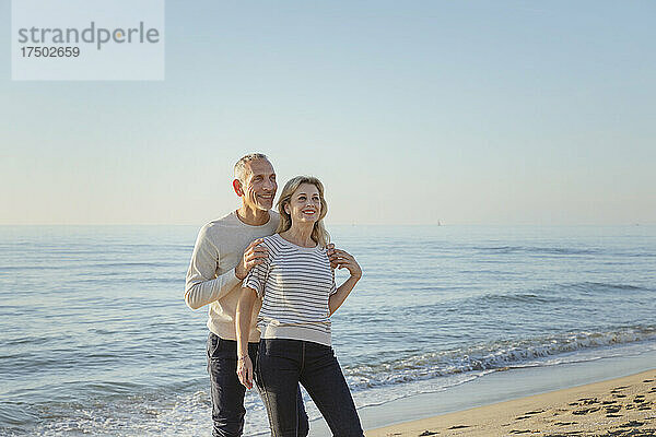 Lächelndes Paar in der Nähe der Küste am Strand