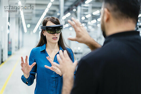 Geschäftsfrau nutzt Augment-Reality-Brille und diskutiert mit Ingenieur in der Industrie
