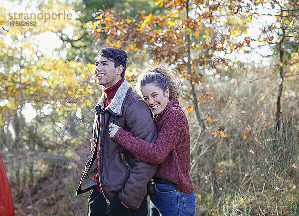Lächelnde Frau umarmt Freund im Herbstwald
