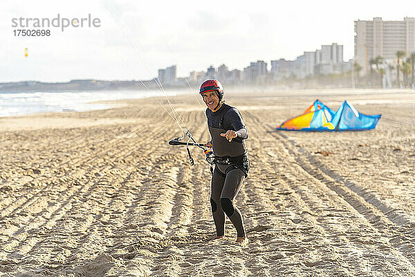 Lächelnder Mann mit Sporthelm steht auf Sand