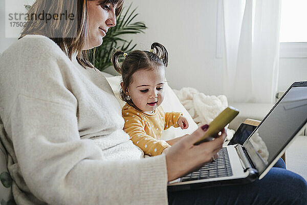 Mutter benutzt Laptop mit Tochter zu Hause