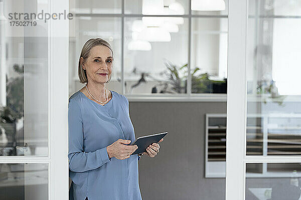 Ältere Geschäftsfrau hält Tablet-PC vor der Tür