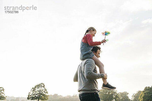 Vater trägt Tochter auf Schultern im Park